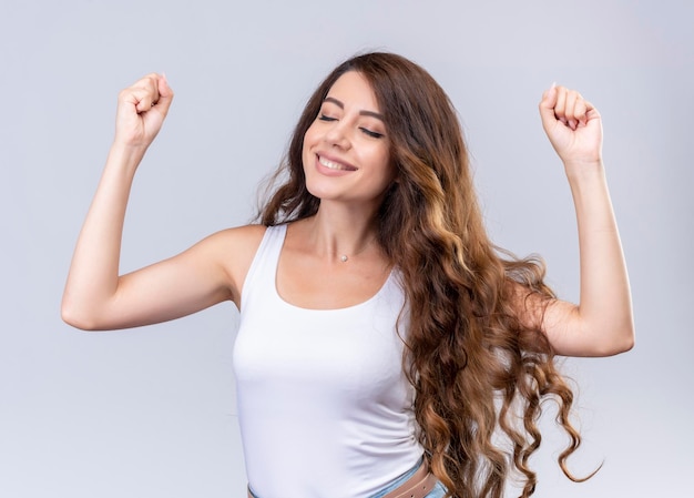 Linda jovem sorridente levantando os punhos com os olhos fechados