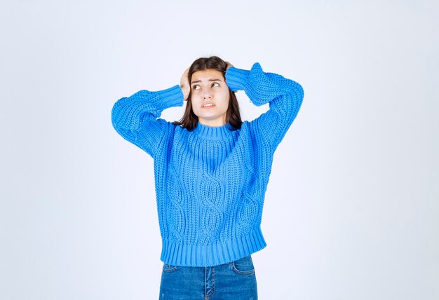 Linda jovem vestindo um suéter azul de mãos dadas na cabeça.