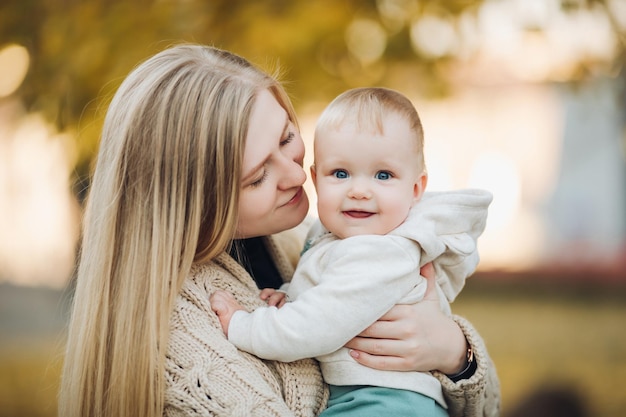 Linda mãe e filha andando no parque no retrato de outono conceito de família mãe e filha uma garotinha nos braços da mãe