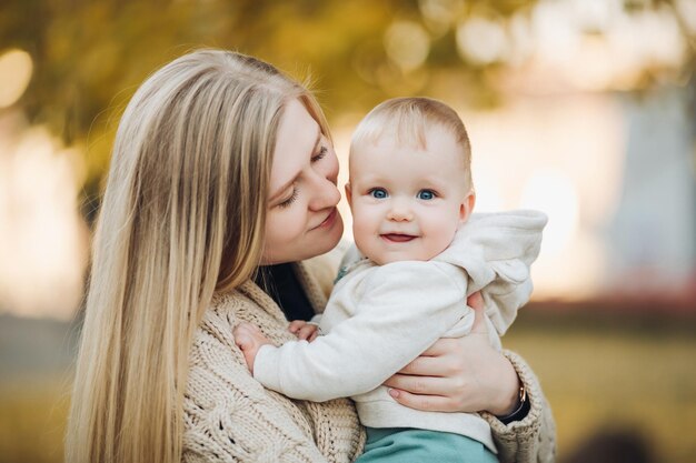 Linda mãe e filha andando no parque no retrato de outono Conceito de família mãe e filha Uma garotinha nos braços da mãe