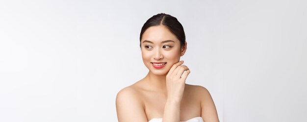Linda maquiagem de mulher asiática de menina cosmética toca a bochecha e sorri o rosto de beleza perfeito com bem-estar isolado no fundo branco