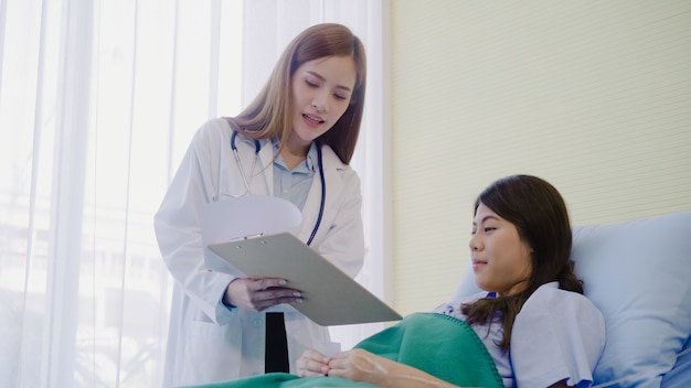 Linda médica asiática inteligente e paciente discutindo e explicando algo com a área de transferência