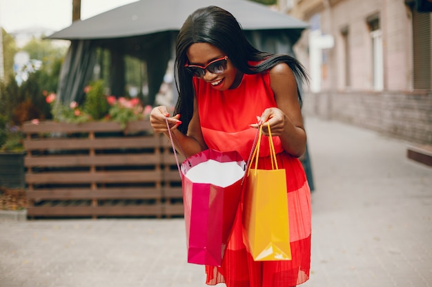 Linda menina negra com sacos de compras em uma cidade