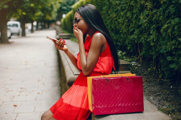 Linda menina negra com sacos de compras em uma cidade