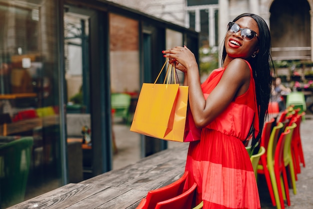 Linda menina negra com sacos de compras em uma cidade