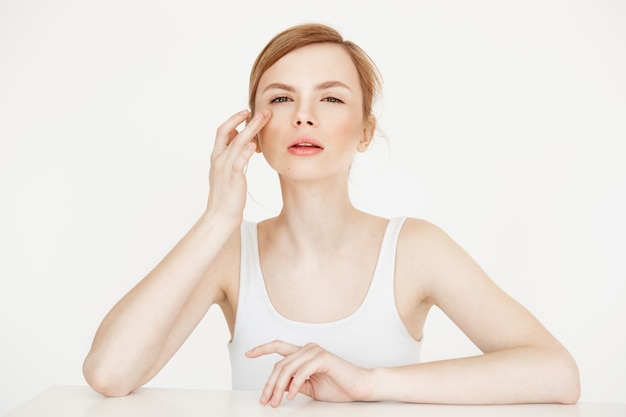 Linda menina tocando a pele, sentado à mesa. Cuidados com a pele cosmetologia e beleza.