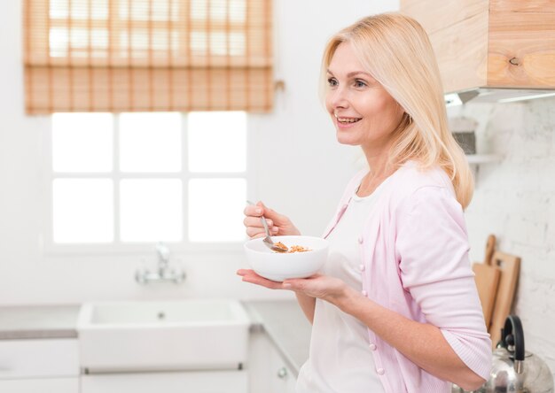 Linda mulher adulta servindo café da manhã na cozinha