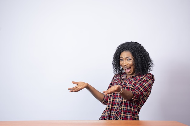 Foto grátis linda mulher africana gesticulando para o espaço vazio ao seu lado com empolgação