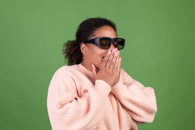Linda mulher afro-americana na parede verde com óculos de cinema 3d feliz, alegre positiva