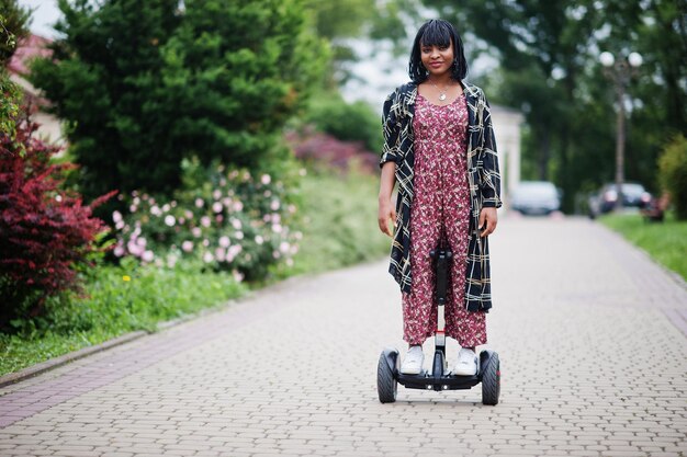 Linda mulher afro-americana usando segway ou hoverboard Garota negra na scooter elétrica de auto-equilíbrio de roda dupla