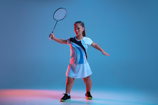 Linda mulher anã praticando badminton isolada em azul em luz de néon