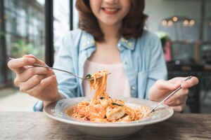 Linda mulher asiática feliz comendo um prato de espaguete de frutos do mar italiano no restaurante ou café enquanto