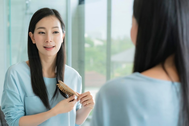 Linda mulher asiática maquiagem e cabelo com espelho no banheiro com luz da manhã