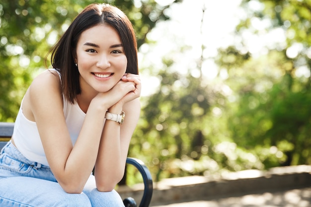 Linda mulher asiática sentada no banco e sorrindo