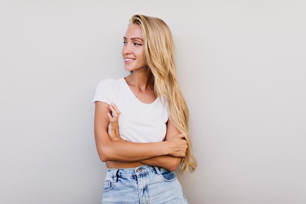 Linda mulher bronzeada com penteado longo, olhando para longe. Mulher sensual e alegre sorrindo