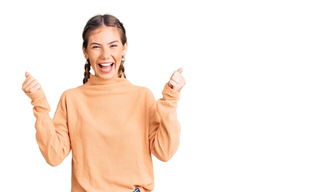 Linda mulher caucasiana com cabelo loiro vestindo suéter de inverno casual celebrando surpreso e espantado pelo sucesso com os braços levantados e olhos abertos. conceito de vencedor.