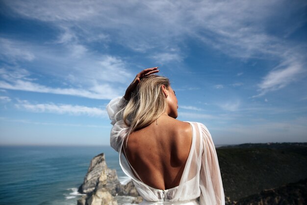 Linda mulher com as costas nuas fica na vista panorâmica da costa