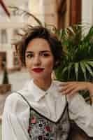 Foto grátis linda mulher com cabelo curto numa blusa elegante em restaurante. mulher encantadora com lábios brilhantes sorri no café.