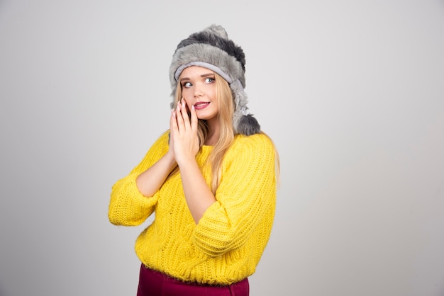 Linda mulher com chapéu de inverno, olhando para o lado dela.