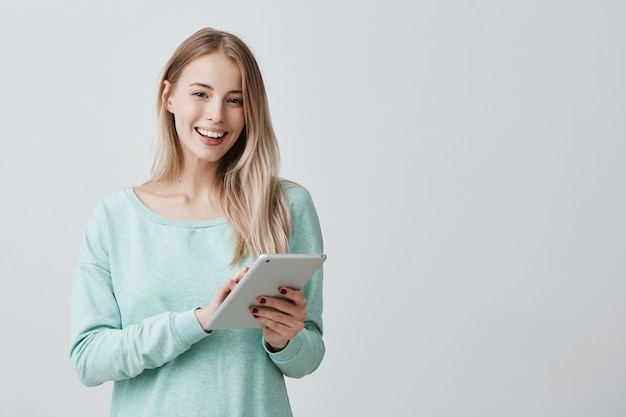 Linda mulher com longos cabelos loiros usando tablet para educação ou trabalho na compilação de gráficos de negócios.