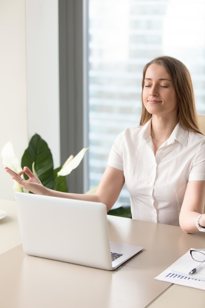 Linda mulher de negócios meditando no escritório