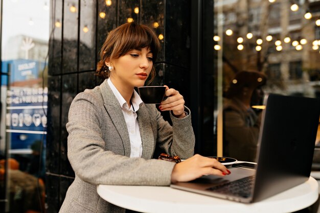 Linda mulher de terno com fones de ouvido e laptop trabalhando