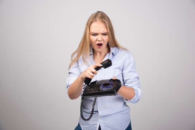 Linda mulher desligando a parede cinza de telefone isolado.