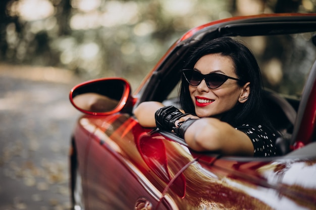 Linda mulher dirigindo um cabrio vermelho