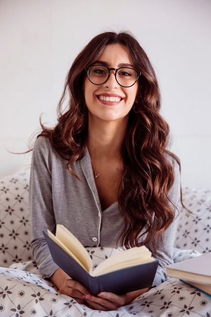 Foto grátis linda mulher em óculos lendo na cama