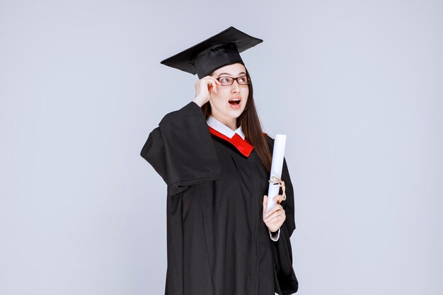 Linda mulher em um vestido com diploma de graduação na faculdade. Foto de alta qualidade