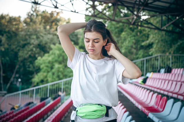 Foto grátis linda mulher esportiva amarrando o cabelo antes do treino no estádio