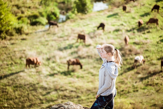 Foto grátis linda mulher esportiva em pé no campo de pedra com fundo de vacas.