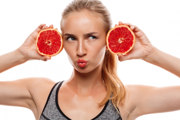 Linda mulher esportiva posando, segurando a toranja