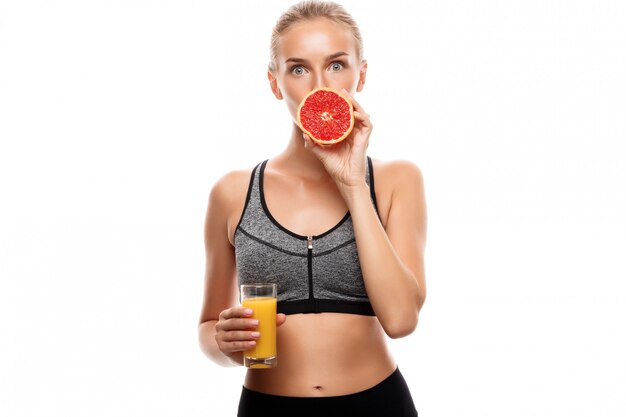 Linda mulher esportiva segurando toranja e suco