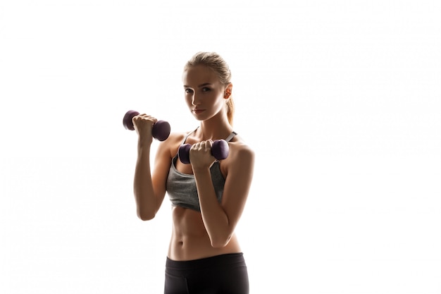 Linda mulher esportiva treinando com halteres