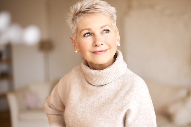 Linda mulher feliz aposentada com suéter confortável e penteado curto