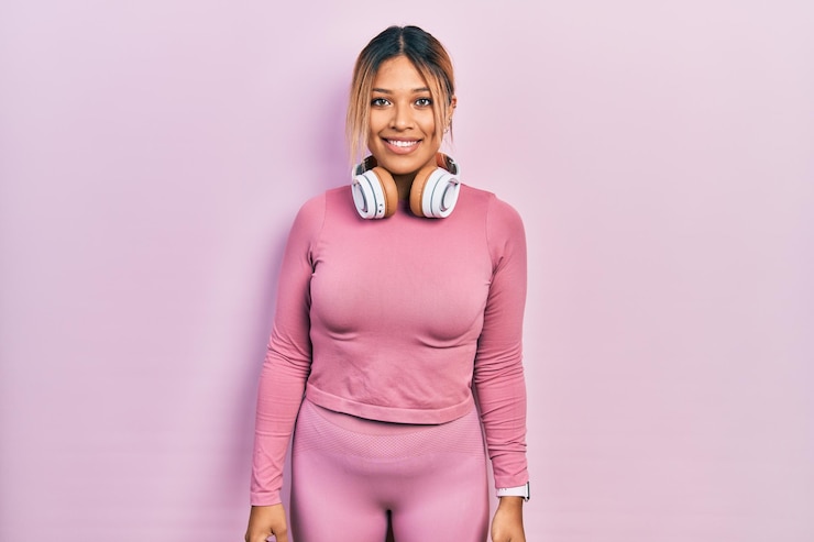 Foto grátis linda mulher hispânica vestindo roupas de ginástica e usando fones de ouvido com um sorriso feliz e legal no rosto pessoa de sorte