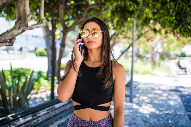 Linda mulher latina falando ao telefone e sorrindo em um parque