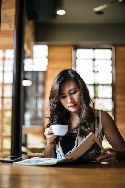 Linda mulher lendo revista no café