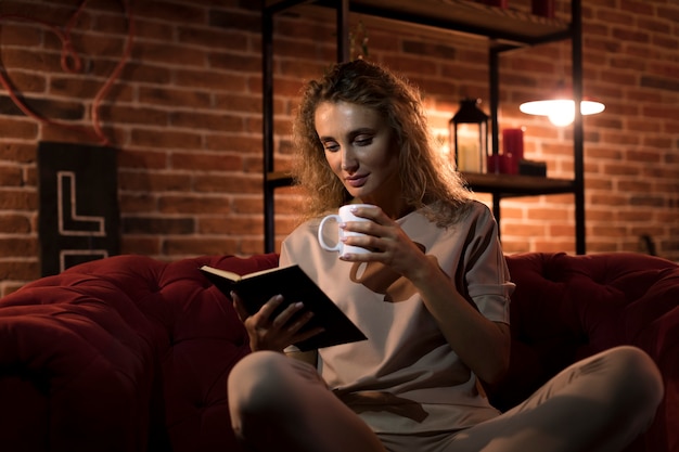 Linda mulher lendo um livro em casa