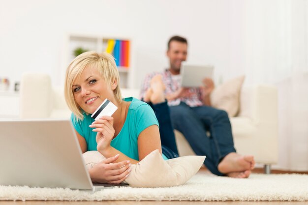Linda mulher loira relaxando em casa com laptop e cartão de crédito