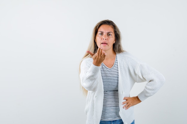 Linda mulher mantendo a mão de maneira questionadora na jaqueta e olhando ansiosa, vista frontal.