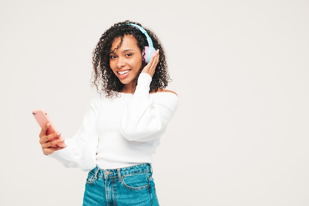 Linda mulher negra com penteado de cachos afro. Modelo sorridente de suéter e jeans