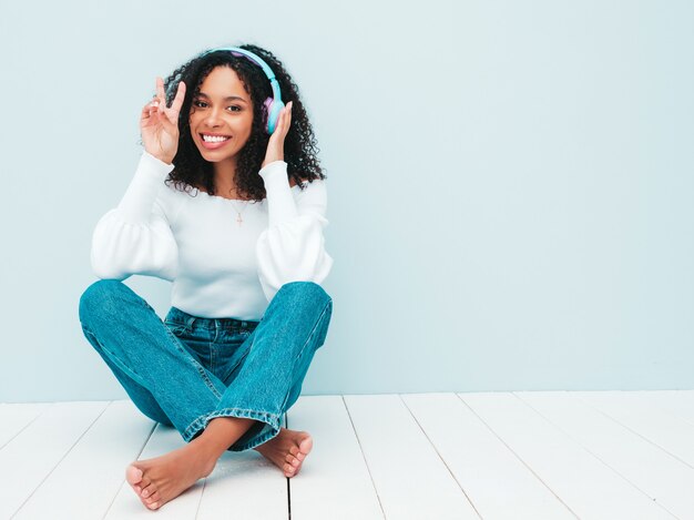 Linda mulher negra com penteado de cachos afro. Modelo sorridente de suéter e jeans