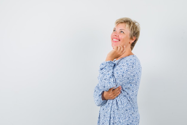 Linda mulher segurando a mão em seu queixo na blusa estampada e olhando ansiosa, vista frontal. espaço para texto