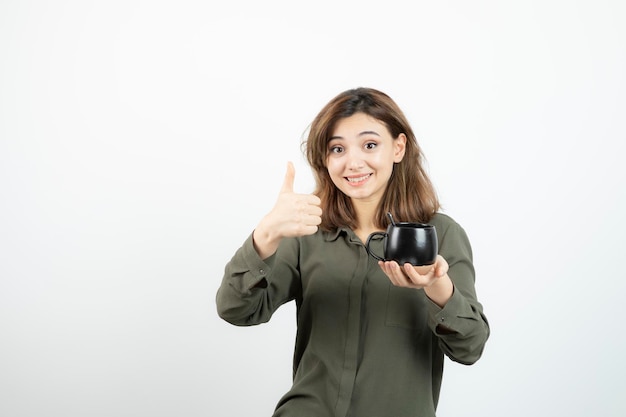 Linda mulher segurando a xícara de café e dando os polegares para cima. Foto de alta qualidade