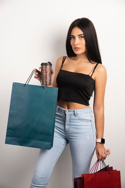 Linda mulher segurando café e sacolas de compras. Foto de alta qualidade