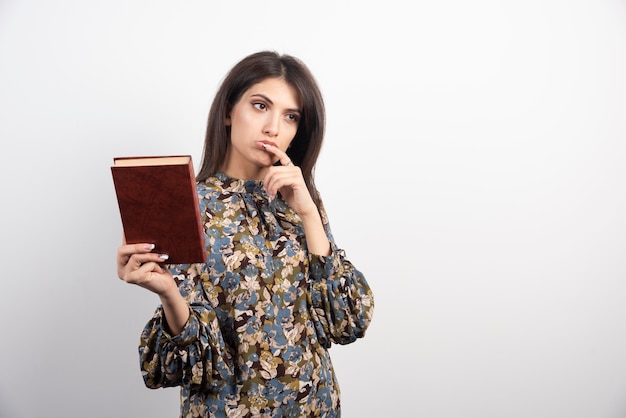 Linda mulher segurando o livro e pensando.