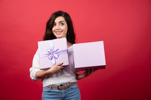 Linda mulher segurando roxo presente sobre fundo vermelho. Foto de alta qualidade