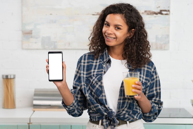 Foto grátis linda mulher segurando um copo de suco e um telefone simulado